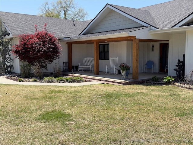 exterior space with covered porch, a shingled roof, and a front lawn