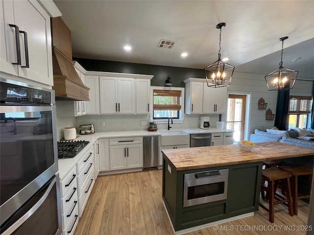 kitchen featuring visible vents, appliances with stainless steel finishes, a sink, butcher block counters, and a chandelier