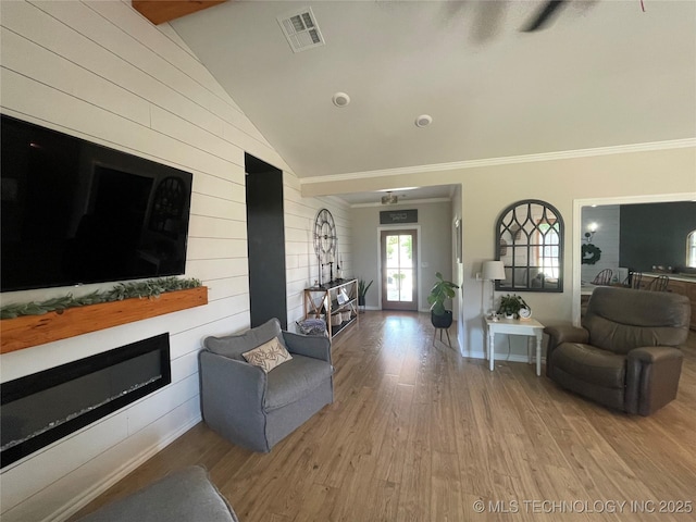 living area with wooden walls, visible vents, wood finished floors, and lofted ceiling