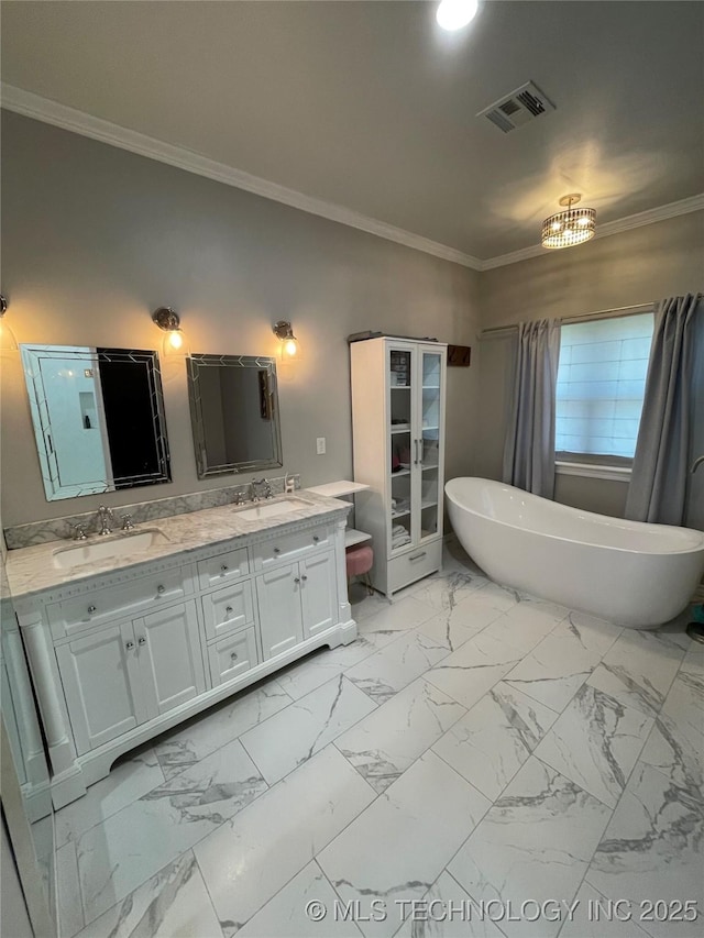 full bath with double vanity, a freestanding tub, visible vents, and a sink