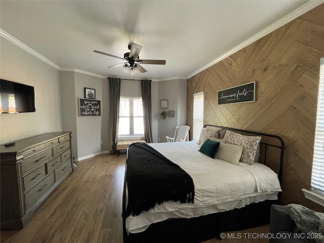 bedroom featuring baseboards, ornamental molding, wood finished floors, and wooden walls