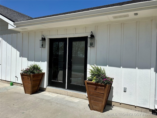 property entrance with roof with shingles, a patio, and board and batten siding