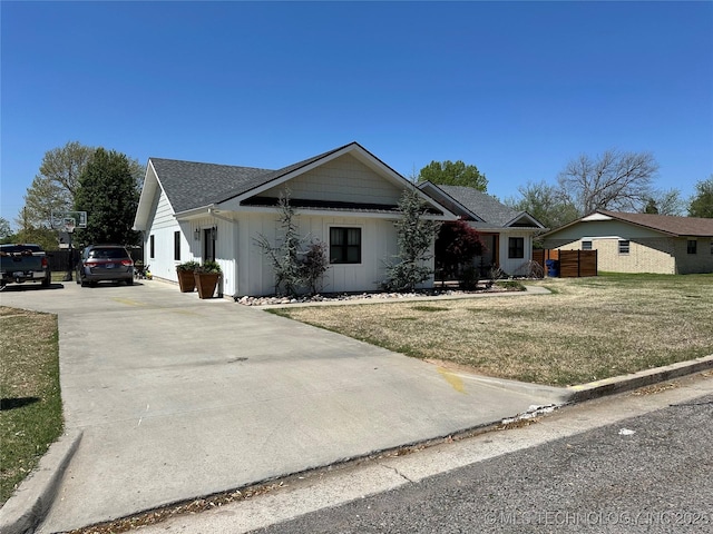 ranch-style house with roof with shingles, board and batten siding, concrete driveway, and a front yard