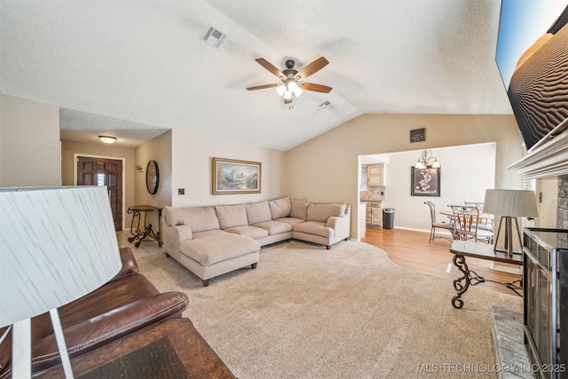 living room featuring visible vents, ceiling fan, light colored carpet, vaulted ceiling, and a textured ceiling