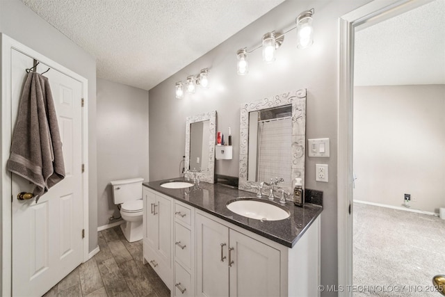 full bath featuring double vanity, a textured ceiling, toilet, and a sink