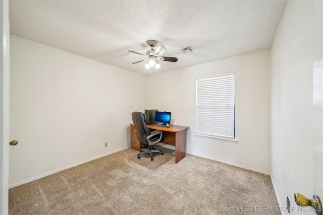 office area featuring visible vents, a textured ceiling, carpet flooring, baseboards, and ceiling fan