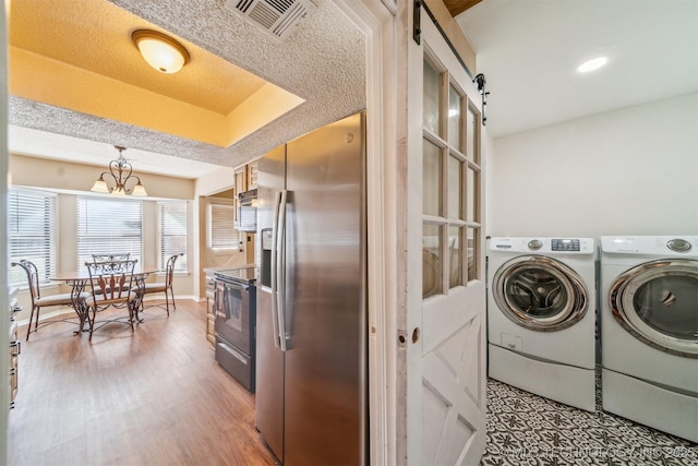 washroom with visible vents, an inviting chandelier, a textured ceiling, washing machine and dryer, and light wood-type flooring