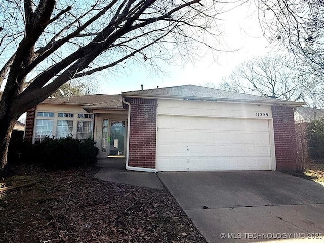 single story home featuring concrete driveway, an attached garage, brick siding, and roof with shingles