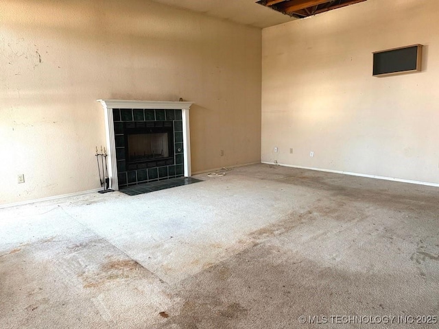 unfurnished living room with a tiled fireplace and carpet floors