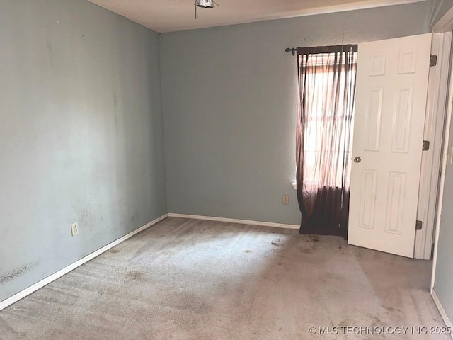 carpeted empty room featuring baseboards