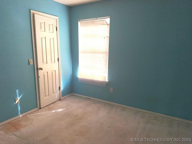 unfurnished room with a wealth of natural light, baseboards, and carpet