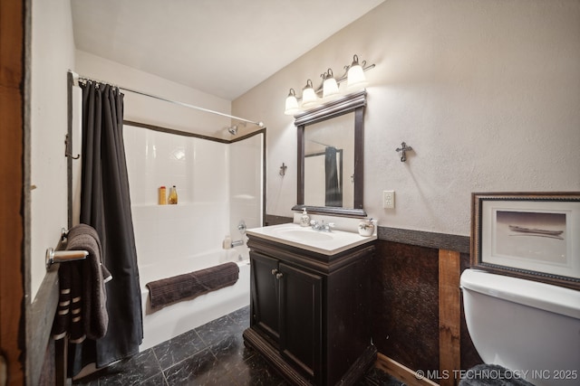 full bath with toilet, marble finish floor, washtub / shower combination, vanity, and a textured wall