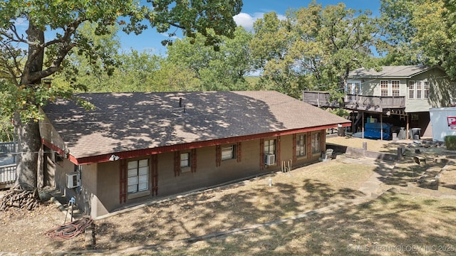 back of house with cooling unit and roof with shingles