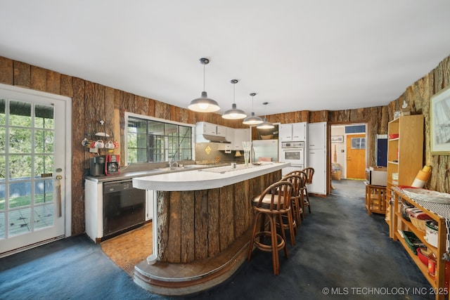 kitchen featuring white appliances, light countertops, wood walls, and a healthy amount of sunlight