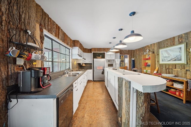 kitchen featuring dark countertops, black dishwasher, stainless steel refrigerator, white cabinetry, and a sink