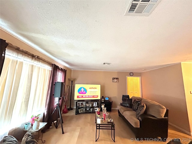 living area with baseboards, visible vents, and a textured ceiling