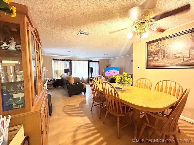 dining room with a textured ceiling, visible vents, and ceiling fan