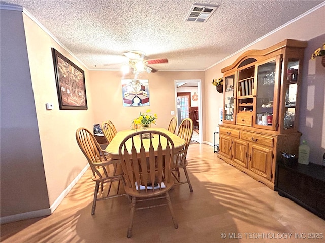 dining area featuring visible vents, baseboards, crown molding, and a ceiling fan