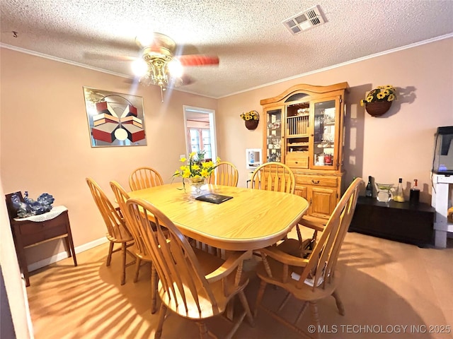 dining area featuring visible vents, a ceiling fan, and ornamental molding