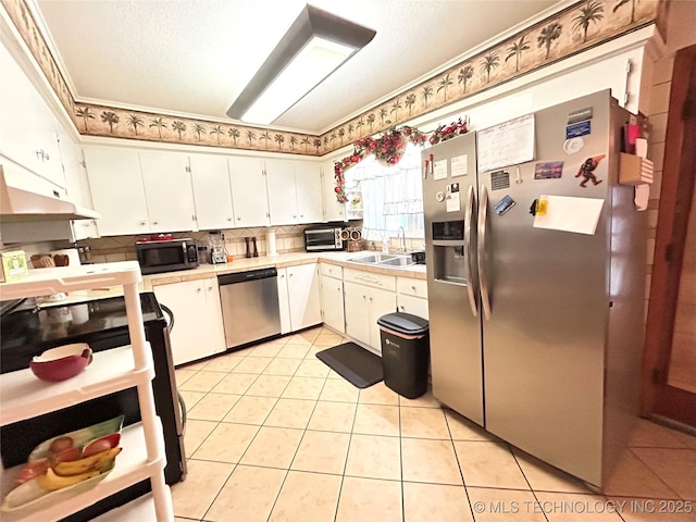 kitchen with a sink, stainless steel appliances, white cabinets, and light tile patterned floors