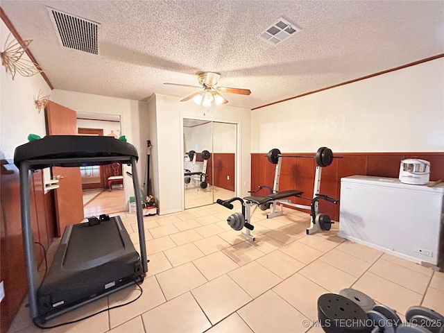 workout room with visible vents, a textured ceiling, ceiling fan, and crown molding