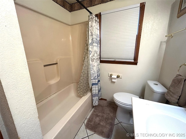 bathroom featuring tile patterned floors, toilet, shower / tub combo with curtain, and a sink