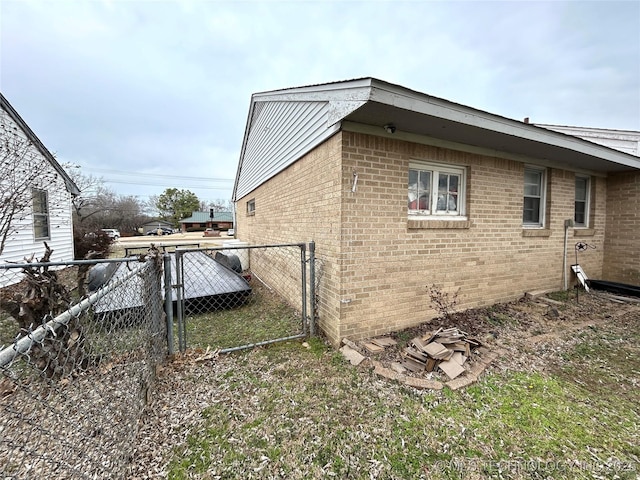 view of side of property featuring fence and brick siding