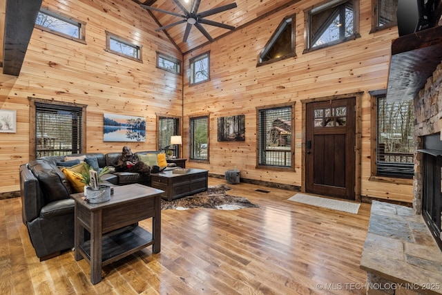 living area featuring wood finished floors, wooden walls, a fireplace, lofted ceiling, and ceiling fan