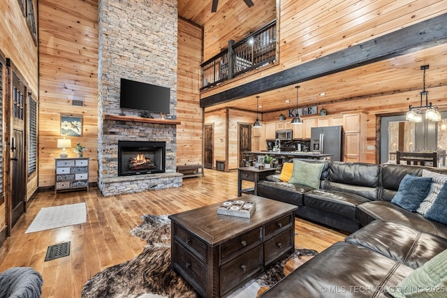 living room featuring wooden walls, a fireplace, light wood-type flooring, and a high ceiling