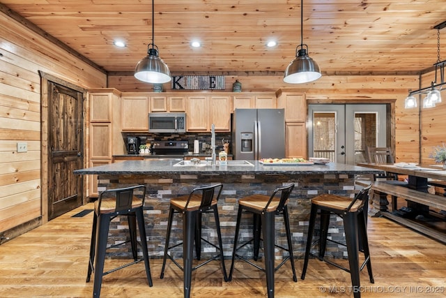 kitchen featuring a center island with sink, light brown cabinetry, a sink, appliances with stainless steel finishes, and wooden ceiling