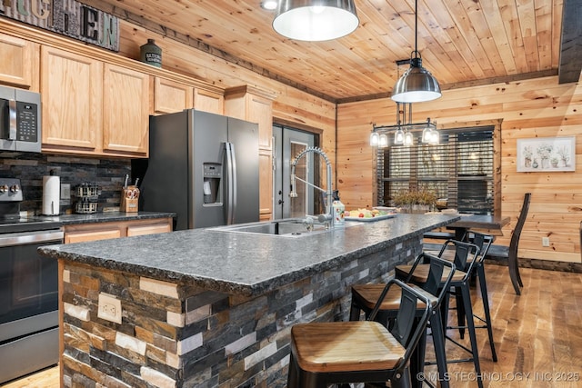 kitchen featuring light brown cabinets, a sink, dark countertops, stainless steel appliances, and wood ceiling