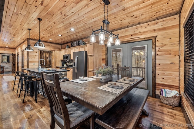 dining room with wooden ceiling, recessed lighting, wood finished floors, and wood walls