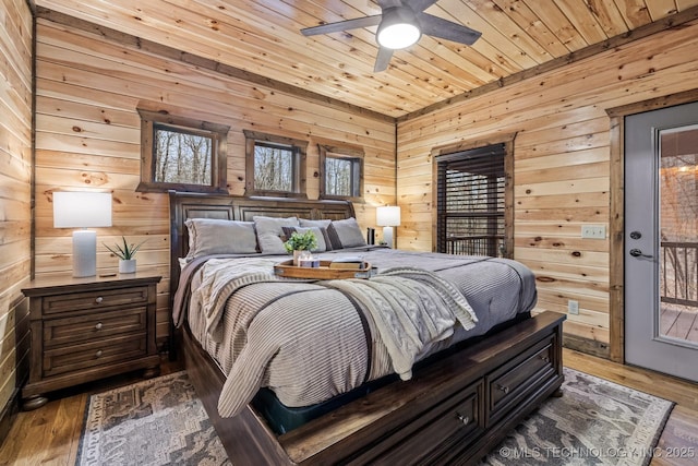 bedroom with wood finished floors, wooden walls, wood ceiling, and ceiling fan