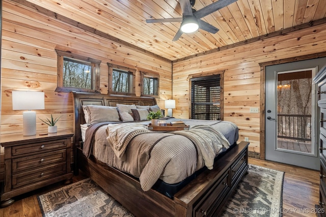 bedroom with wooden walls, wood ceiling, a ceiling fan, and wood finished floors