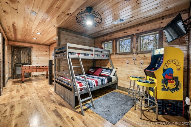 bedroom with visible vents, wooden ceiling, wooden walls, and wood finished floors