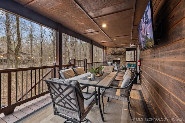 wooden terrace featuring an outdoor stone fireplace and outdoor dining space