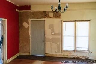 unfurnished room featuring baseboards, wood finished floors, and a chandelier