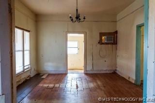 spare room featuring a notable chandelier, a wall unit AC, and hardwood / wood-style flooring