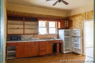 kitchen featuring open shelves, stainless steel microwave, brown cabinetry, light countertops, and ceiling fan