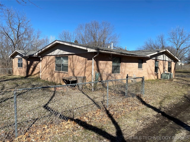 view of property exterior with brick siding, central AC unit, and fence