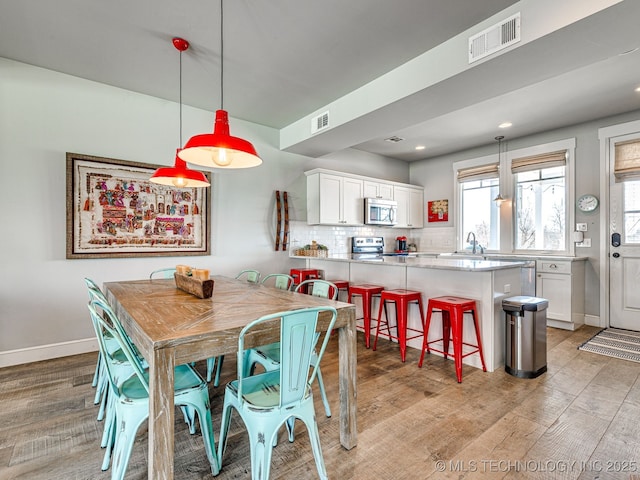 dining room featuring light wood-style flooring, baseboards, and recessed lighting
