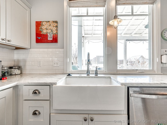 kitchen with stainless steel dishwasher, a sink, healthy amount of natural light, and tasteful backsplash