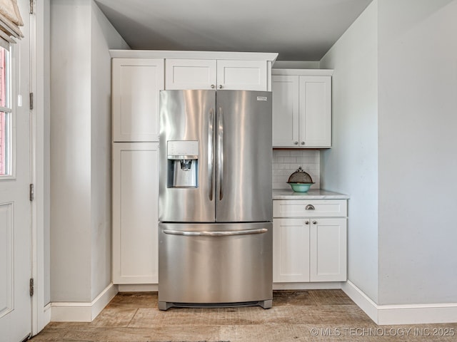 kitchen featuring stainless steel fridge with ice dispenser, backsplash, light wood-style floors, baseboards, and white cabinetry