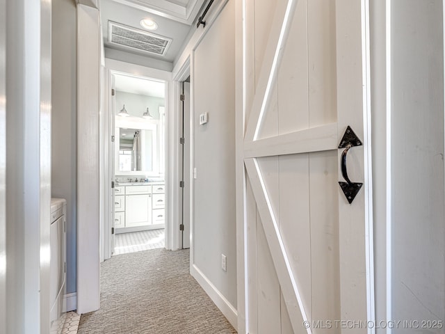 hall with light carpet, washing machine and clothes dryer, and baseboards