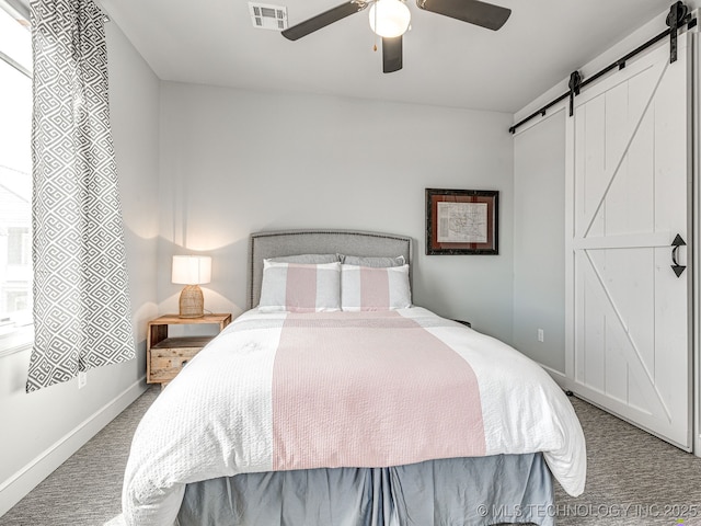 bedroom featuring a barn door, carpet floors, baseboards, and ceiling fan