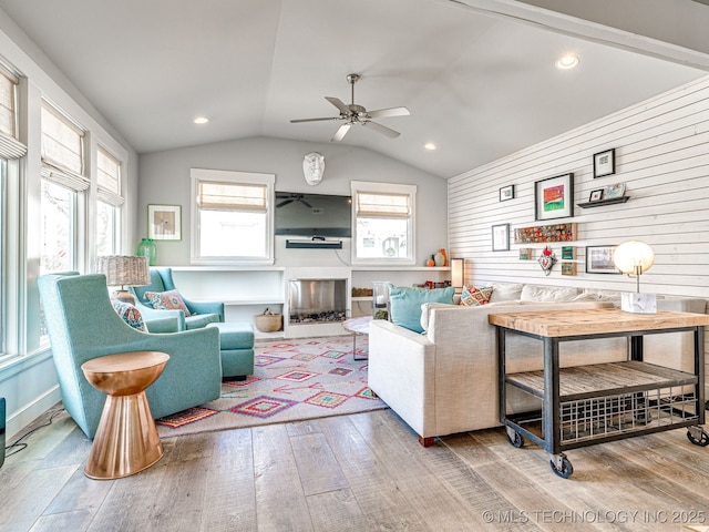 living area with wood finished floors, a ceiling fan, plenty of natural light, vaulted ceiling, and recessed lighting