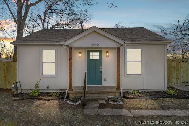 view of front of property with a shingled roof and fence