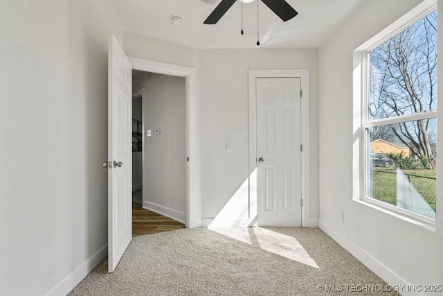 carpeted empty room with a ceiling fan and baseboards