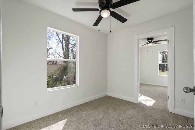 carpeted empty room featuring ceiling fan and baseboards