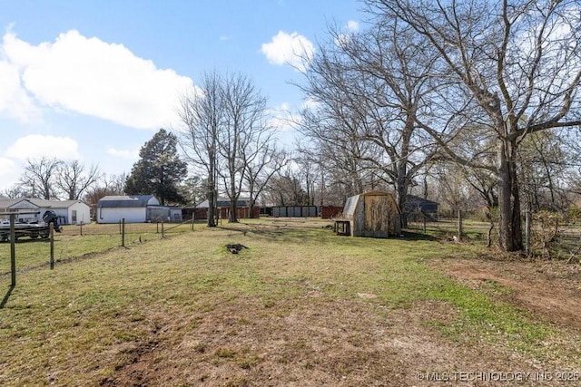 view of yard with an outbuilding, fence, and a shed